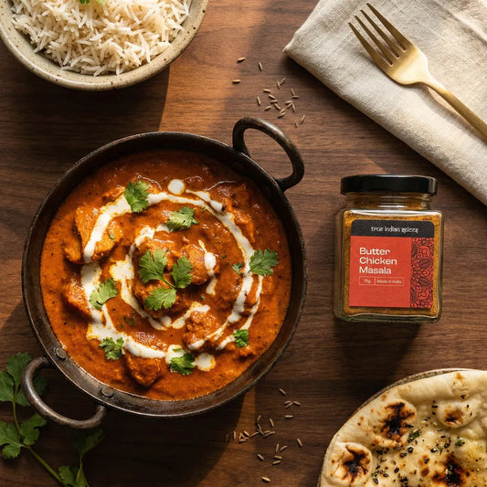 Butter Chicken dish with a jar of Butter Chicken Masala on a wooden table.