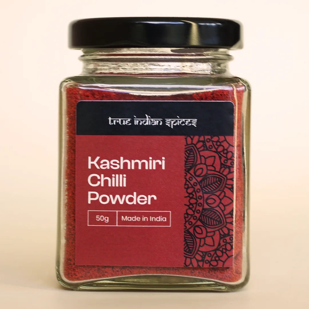 Glass jar of True Indian Spices Kashmiri Chilli Powder, 50g, made in India, with black lid and red decorative label featuring traditional Indian pattern