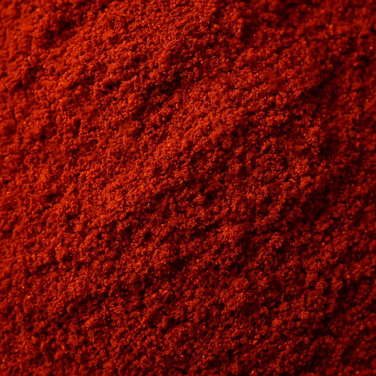 Close-up texture of vibrant red Kashmiri chilli powder showing fine, powdery consistency and deep crimson colour