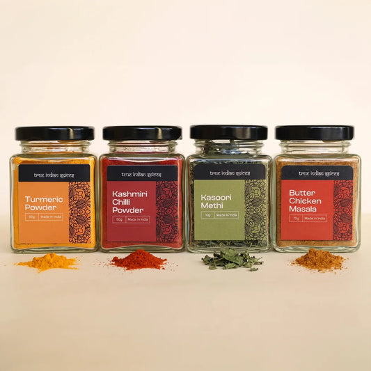 Four jars of spices with visible spices on a beige background