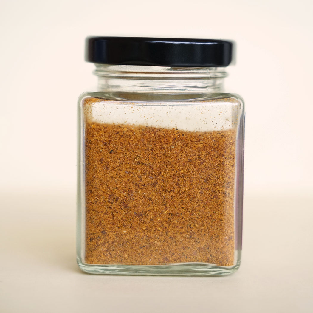 Close-up of back of a jar filled with butter chicken spice mix, featuring a colourful blend of Indian spices.