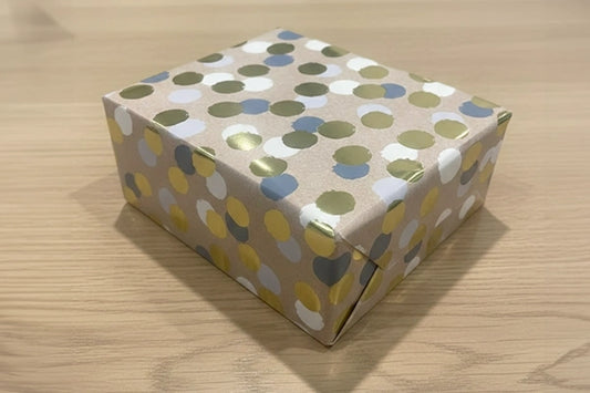 Box wrapped in paper with a polka dot pattern on a wooden surface