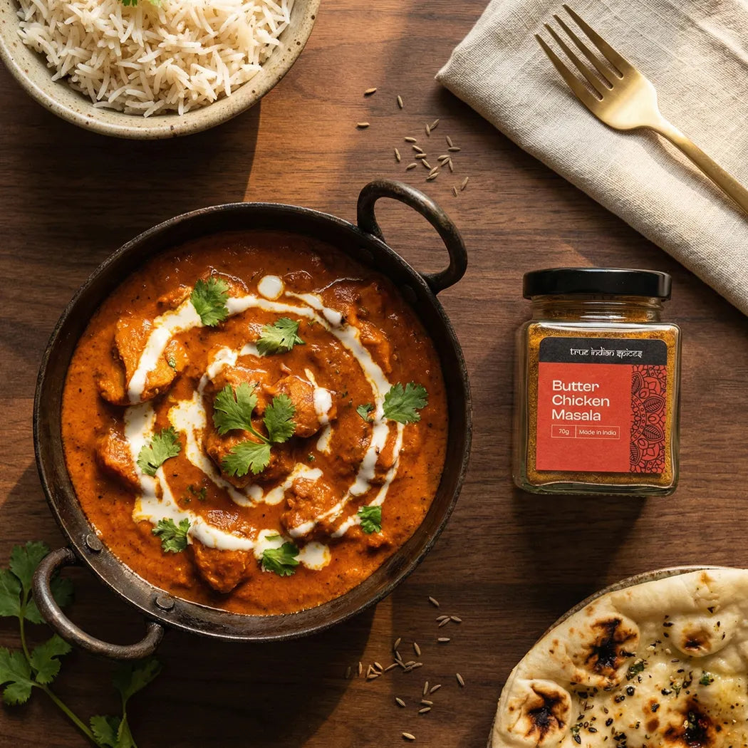 Butter Chicken dish with a jar of Butter Chicken Masala on a wooden table.