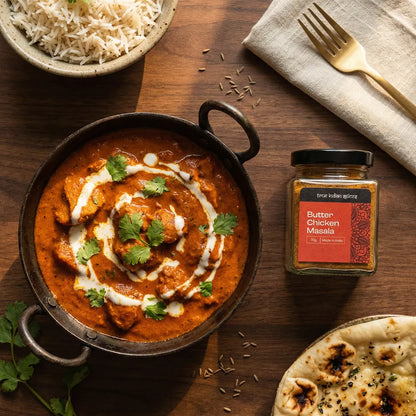 Butter Chicken dish with a jar of Butter Chicken Masala on a wooden table.