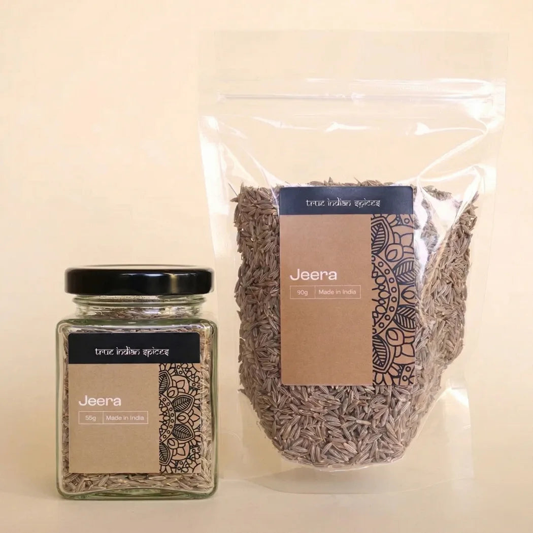 Jar and transparent packaging of 'Jeera' (cumin seeds) with 'True Indian Spices' branding on a beige background.