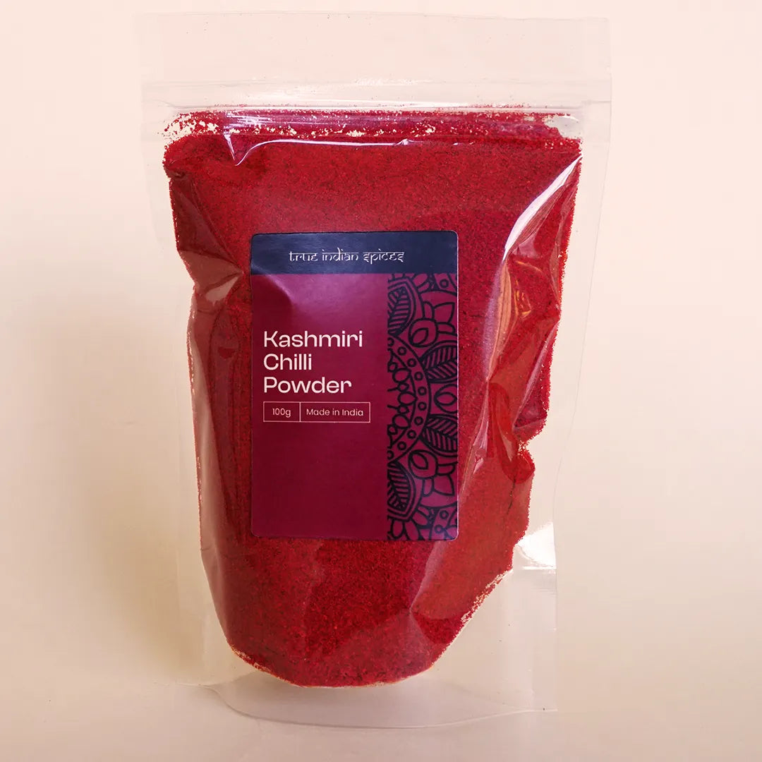 Resealable pouch of True Indian Spices Kashmiri Chilli Powder, 100g, showing the bright red powder through clear packaging with branded label