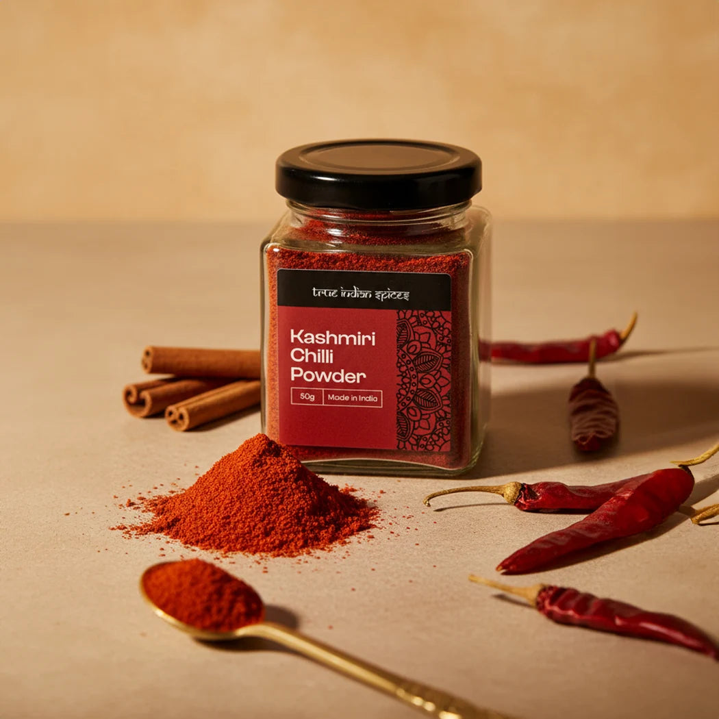 Jar of Kashmiri Chilli Powder with chili peppers and cinnamon sticks on a beige background