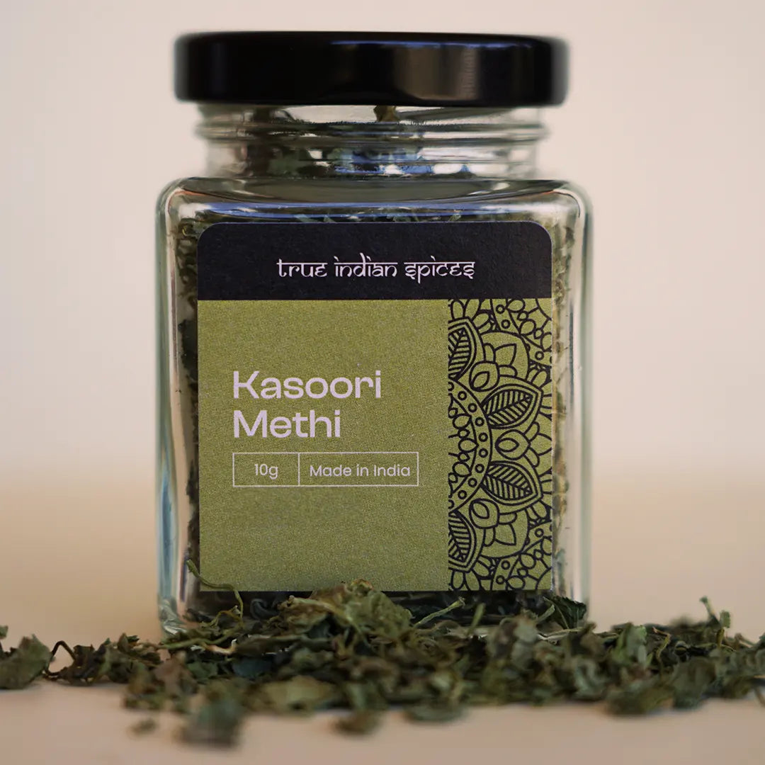 A glass jar with a black lid containing dried fenugreek leaves, labeled 'Kasoori Methi', indicating it is an Indian spice.